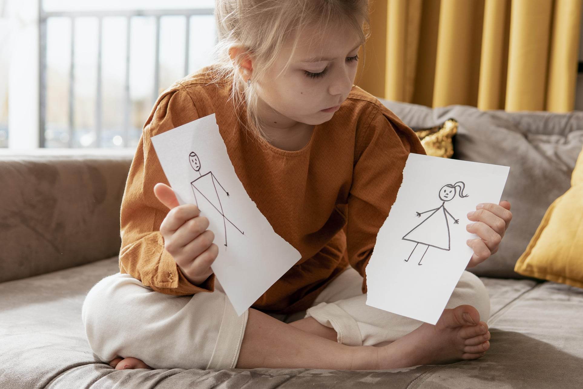 Fetiță blondă care a rupt un desen în care se află părinții ei care s-au despărțit