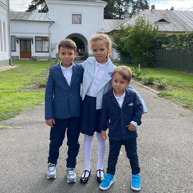 Cei trei copii ai Mirelei Vaida în fața bisericii, în 2022, la începutul anului școlar
