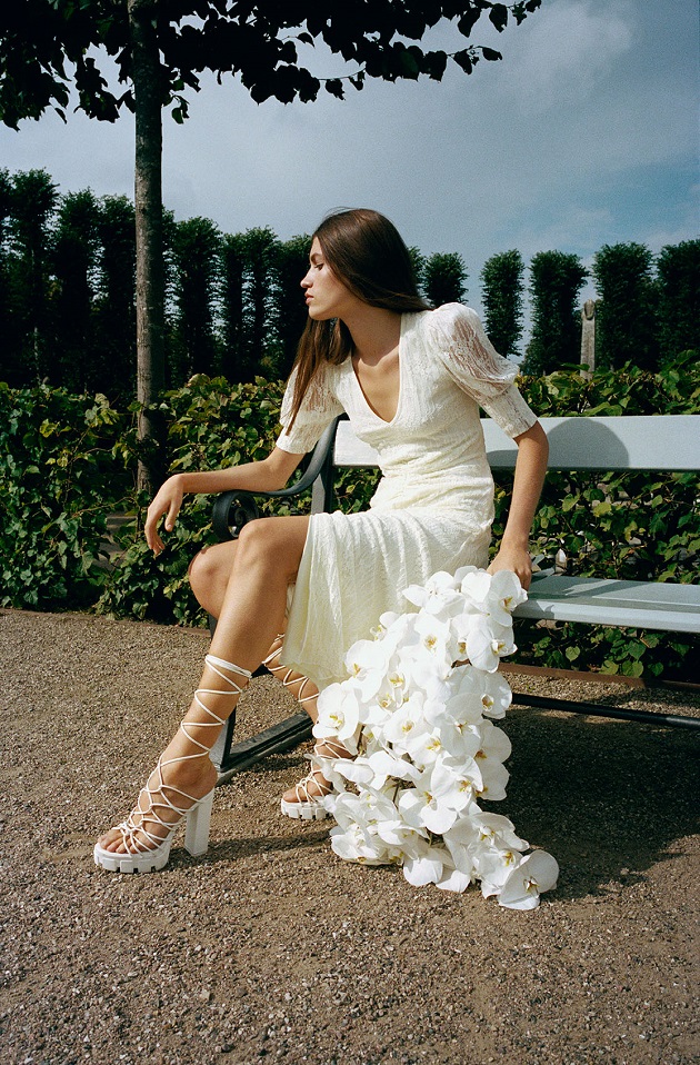 femeie in rochie alba pe banca