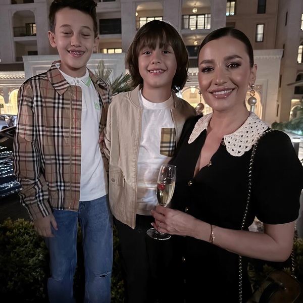 claudia patrascanu cu un pahar de sampanie in mana alaturi de cei doi fii ai sai