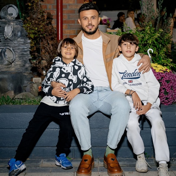 gabi badalau imbracat in blugi si hanorac isi tine baietii in brate